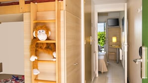 Quarto com escada de madeira, um bicho de pelúcia de macaco, cama, televisão e mesinha com abajur.