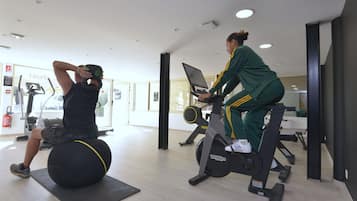 Ein Fitnessraum mit Trainingsgeräten, darunter ein Ergometer und ein Ball.