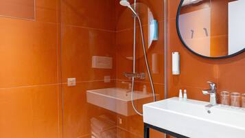 Une salle de bain moderne avec une douche à parois de verre, un lavabo blanc et un miroir.
