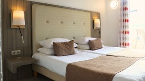 Quarto de hotel com uma cama de casal, duas mesas de cabeceira e uma luminária fixada na parede.