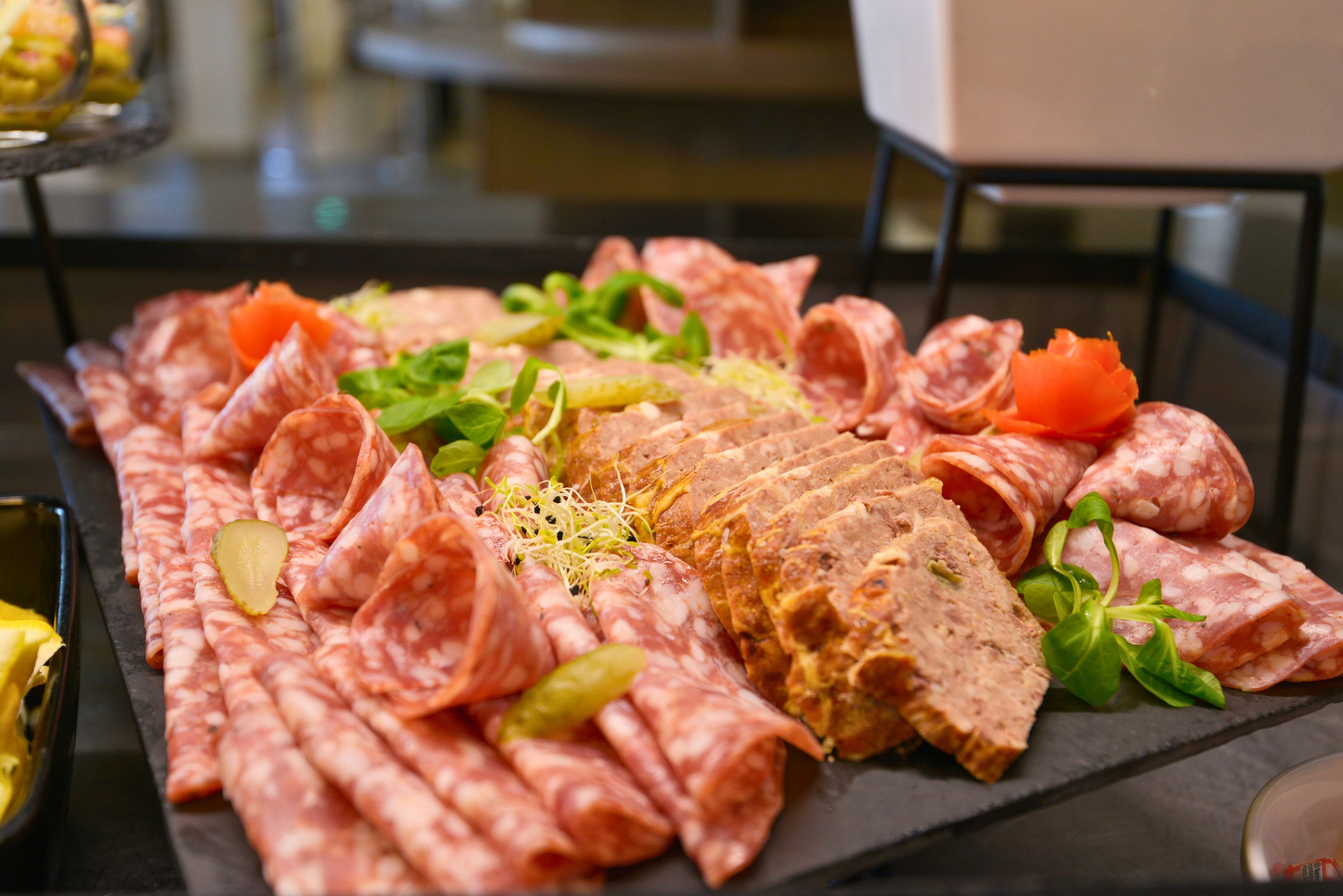A charcuterie board with various meats and garnishes.