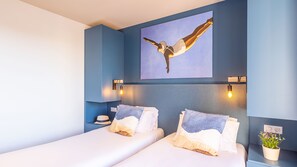 Ein Hotelzimmer mit einem großen Bett, zwei Nachttischen, einem Wandbild und einer Topfpflanze.