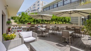 An outdoor patio with wicker furniture, umbrellas, and potted plants. - Studio tout confort au coeur d'Aix-les-Bains (Aix-les-Bains)