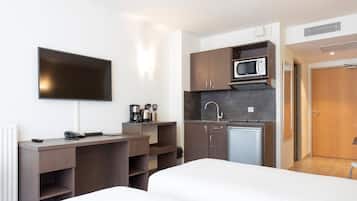 Een hotelkamer met een bed, een bureau, een flatscreen televisie, een kitchenette met een magnetron en een spoelbak.