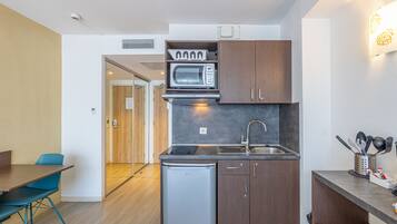 Cocina compacta con microondas, pileta y heladera pequeña. Hay un comedor con mesa y sillas.