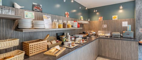 Un espace buffet pour le petit-déjeuner, avec divers plats et ustensiles à disposition.