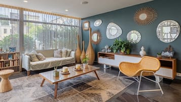 Een moderne woonkamer met een bank, salontafel en decoratieve spiegels aan de muur.
