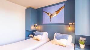 A hotel room with a large bed, two bedside tables, a wall-mounted artwork, and a potted plant. - T3 spacieux à deux pas de la plage | Accès piscine (Le Lavandou)