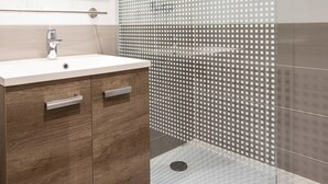 Une salle de bain moderne avec une douche à parois de verre, un meuble-lavabo en bois et un grand miroir.