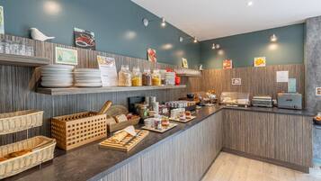 Un espace buffet pour le petit-déjeuner, avec divers plats et ustensiles à disposition.