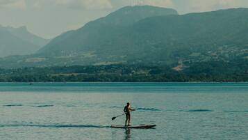 Una persona haciendo paddleboard en aguas tranquilas, con montañas al fondo.