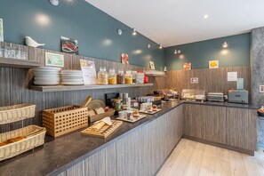 Un área de desayuno tipo buffet con diversos alimentos y utensilios.