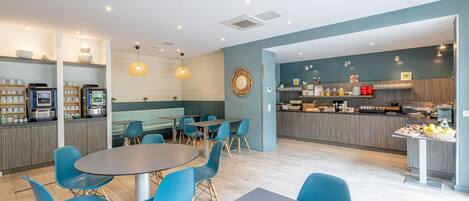 Un restaurant moderne doté d’un bar, d’un espace pour s’asseoir et d’un comptoir où sont présentés des plats.