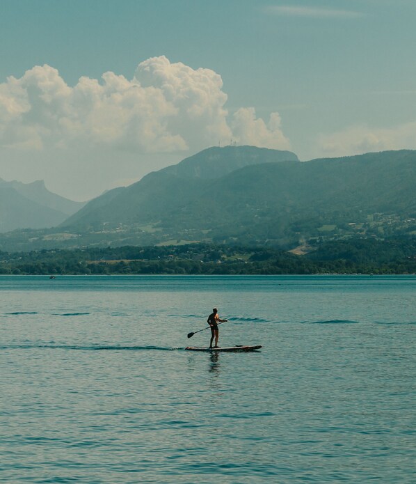A person paddleboarding on a calm body of water with mountains in the background.