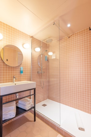 Un bagno moderno con doccia vetro, uno specchio rotondo e un lavandino con portasciuga.
