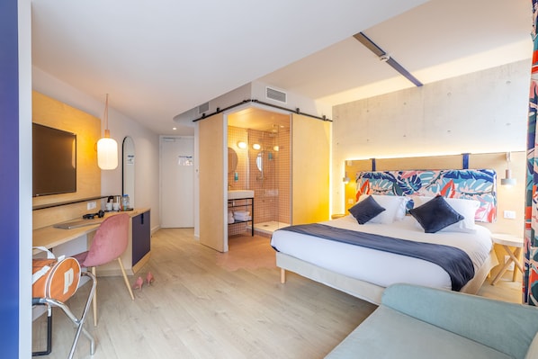 Una camera d'albergo moderna con un letto, una scrivania, una sedia e un angolo doccia.