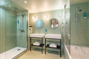Een moderne badkamer met twee wasbakken, een douche met glazen wand en een spiegel met handdoekhouder.