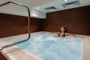 A person relaxing in a hot tub with a wooden wall and ceiling.