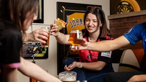 A person holding a glass of beer and a slice of pizza.