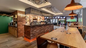 A bar area with a brick counter, shelves with bottles, and a seating area with tables and chairs.