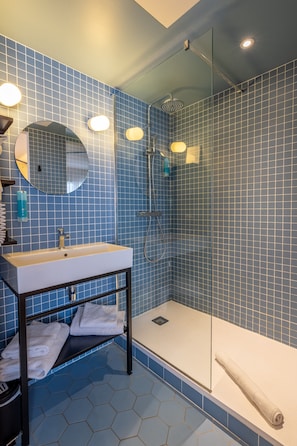 Un bagno moderno con cabina doccia in vetro, uno specchio rotondo e un lavandino bianco.