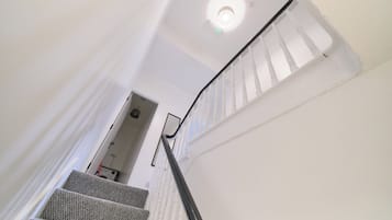 A staircase with white walls and a black handrail leading to a door.