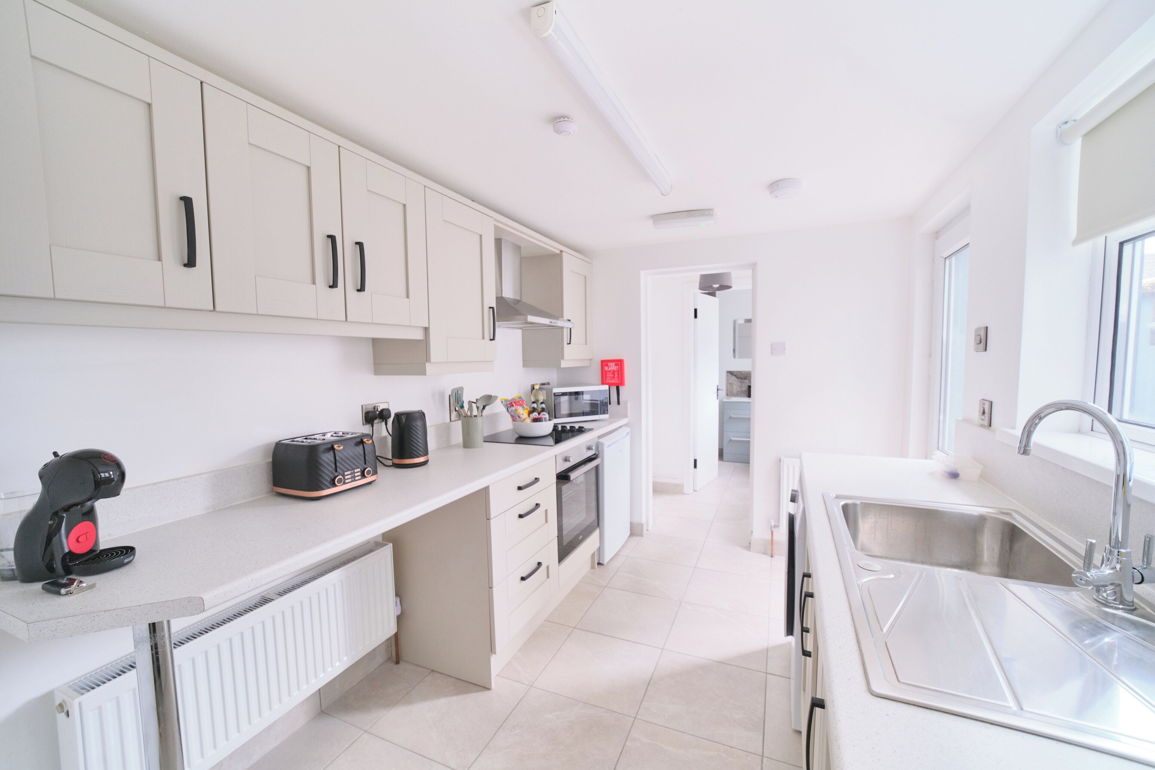 A modern kitchen with white cabinetry, a built-in oven, a microwave, and a sink.