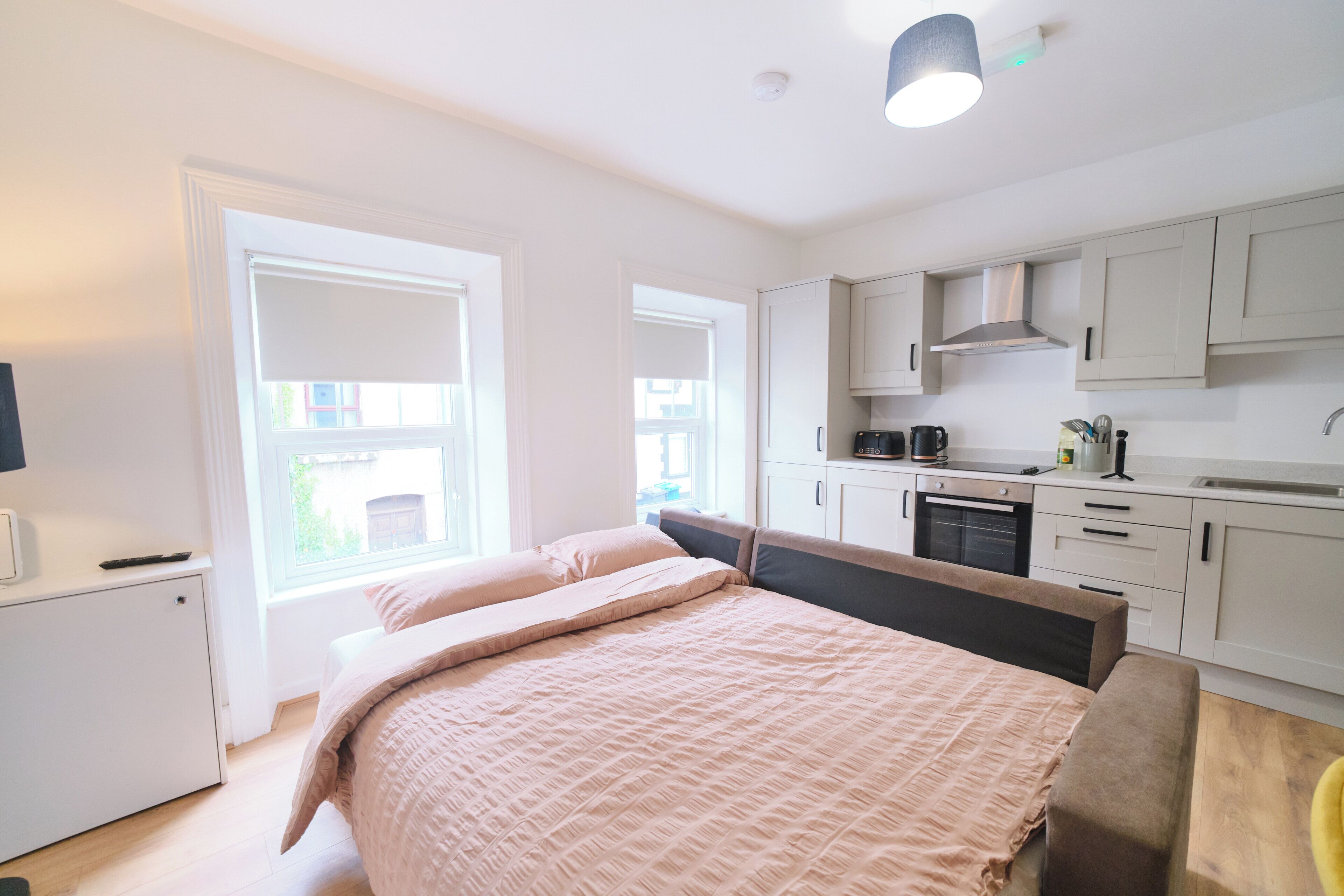 A bedroom with a bed and a kitchenette.