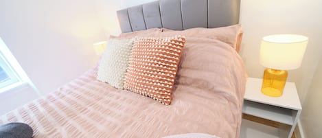 A neatly made bed with a striped bedspread, two pillows, a headboard, and bedside lamps.