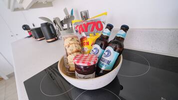 Un comptoir de cuisine avec un bol contenant des biscuits, un pot de confiture et deux bouteilles de bière.