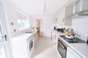 A modern kitchen with a washing machine, oven, and a bowl of snacks on the counter. - Violet and Co (Derry/Londonderry)