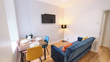 A dining area with a wooden table set for four, a blue sofa, and a floor lamp.