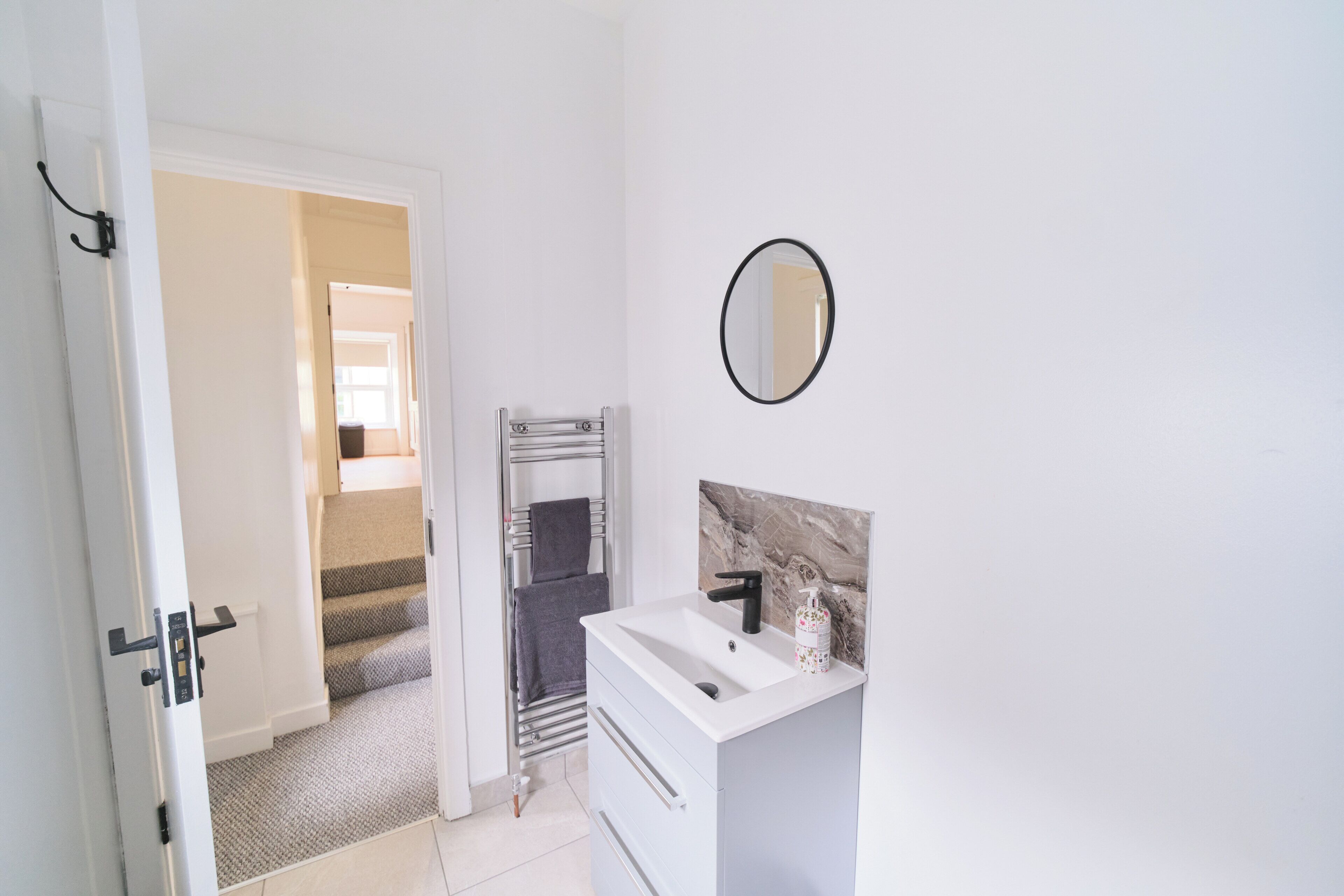 A bathroom with a white sink, a mirror, and a towel rack.