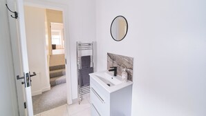 A bathroom with a white sink, a mirror, and a towel rack. - Violet and Co (Derry/Londonderry)