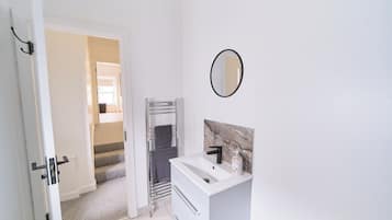 A bathroom with a white sink, a mirror, and a towel rack.