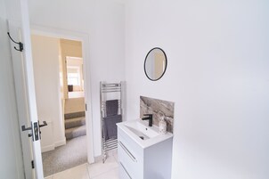 A bathroom with a white sink, a mirror, and a towel rack.