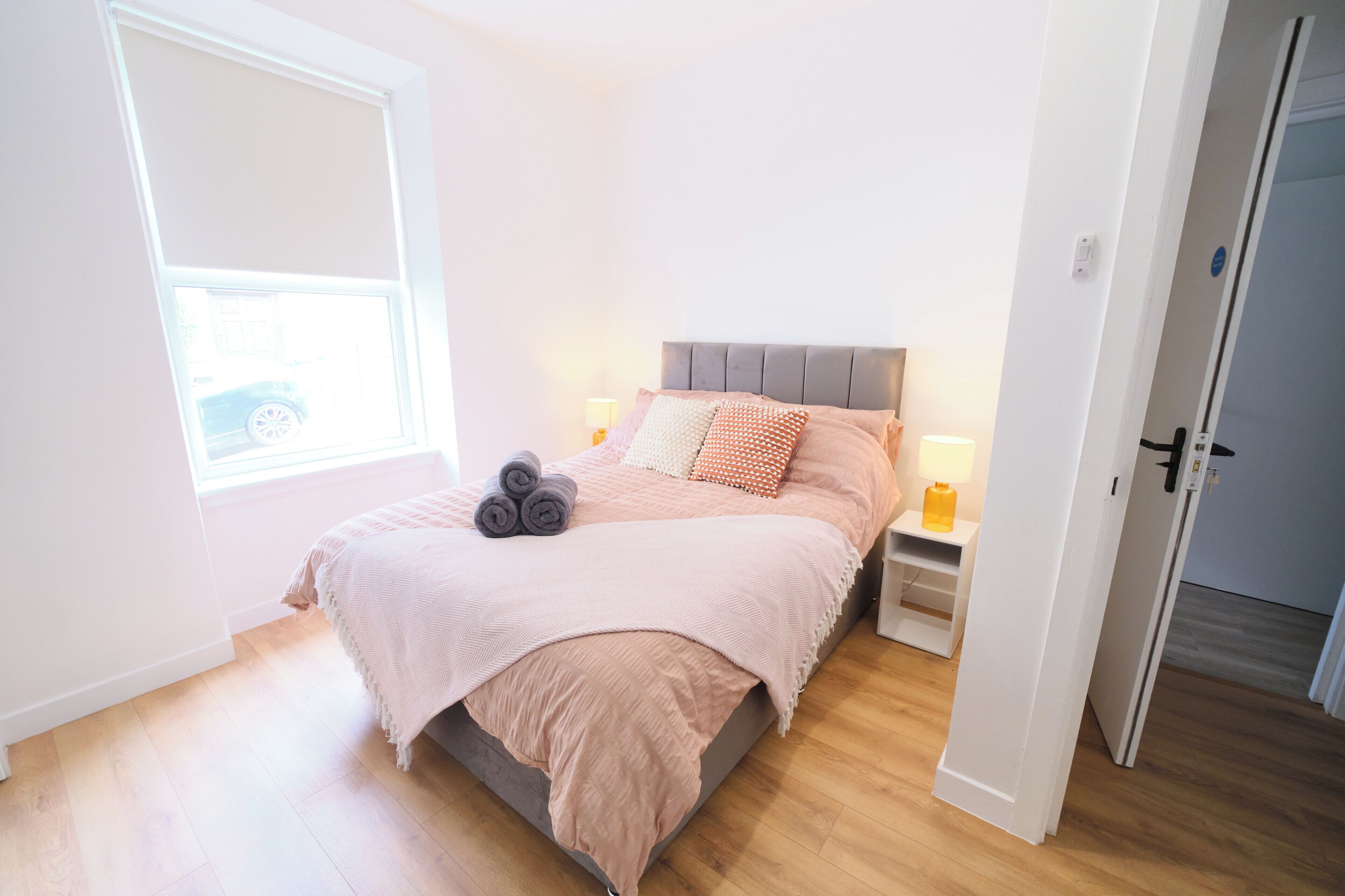 A bedroom with a bed, pillows, a window, and a door.