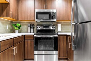 A kitchen with stainless steel appliances, wooden cabinets, and a tiled backsplash. - The Rommie 1BR Highrise w/Fast Wi-Fi, Gym (Denver)