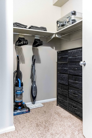 A closet with shelves, a vacuum cleaner, and a storage cabinet. - The Rommie 1BR Highrise w/Fast Wi-Fi, Gym (Denver)
