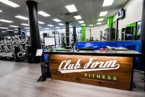 A gym with a reception desk labeled 'Club Form FITNESS' and various exercise equipment. - The Rommie 1BR Highrise w/Fast Wi-Fi, Gym (Denver)
