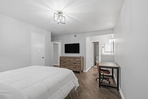 A bedroom with a bed, dresser, TV, and a desk with chair. - Chic 2BR Oasis in Houston (Houston)