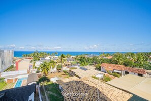 A coastal residential area with houses, a swimming pool, and a view of the ocean. - Apt w/ Balcony & View, Steps From the sea Rgf0410 (Salvador)