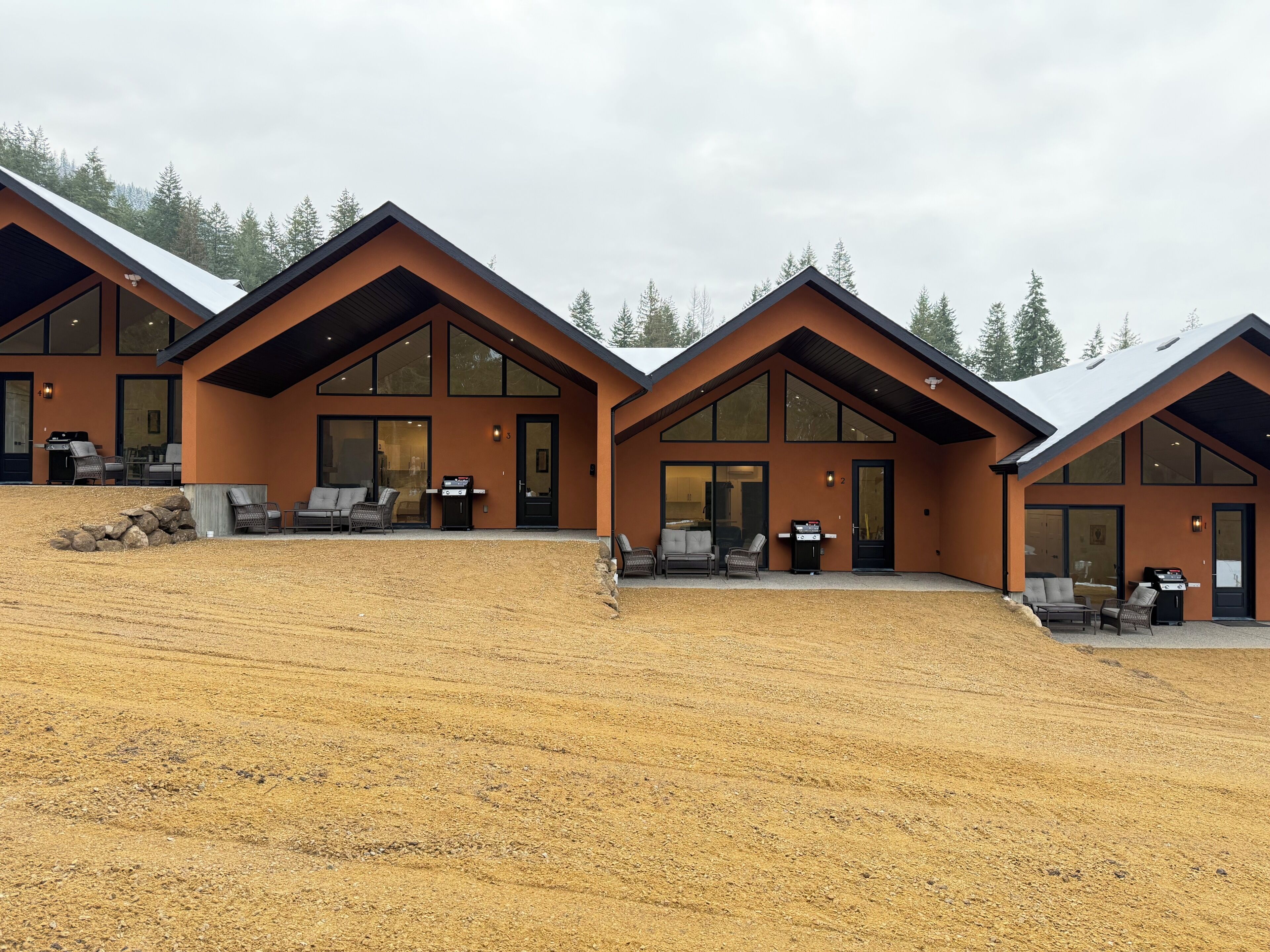 A modern two-story building with large windows and a covered patio area.