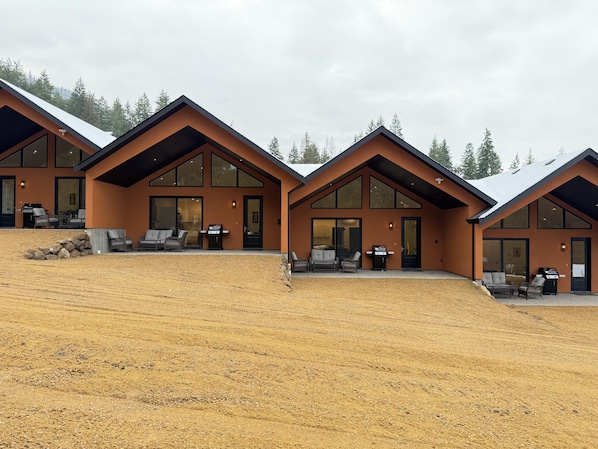 A modern two-story building with large windows and a covered patio area.