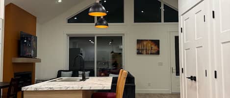 Una cocina amplia con una isla grande, suelo de madera y una lámpara colgante moderna.