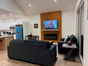 A modern living room with a grey sofa, a fireplace, and a television mounted on a wall.