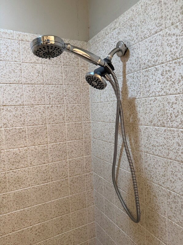 Een douche met een handdouche en een flexibele slang, bevestigd aan een betegelde muur.