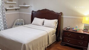 Quarto bem arrumado com cama de madeira, mesas de cabeceira e uma cadeira.