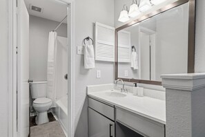 A bathroom with a toilet, sink, and mirror. - Chic 2BR Oasis in Houston (Houston)