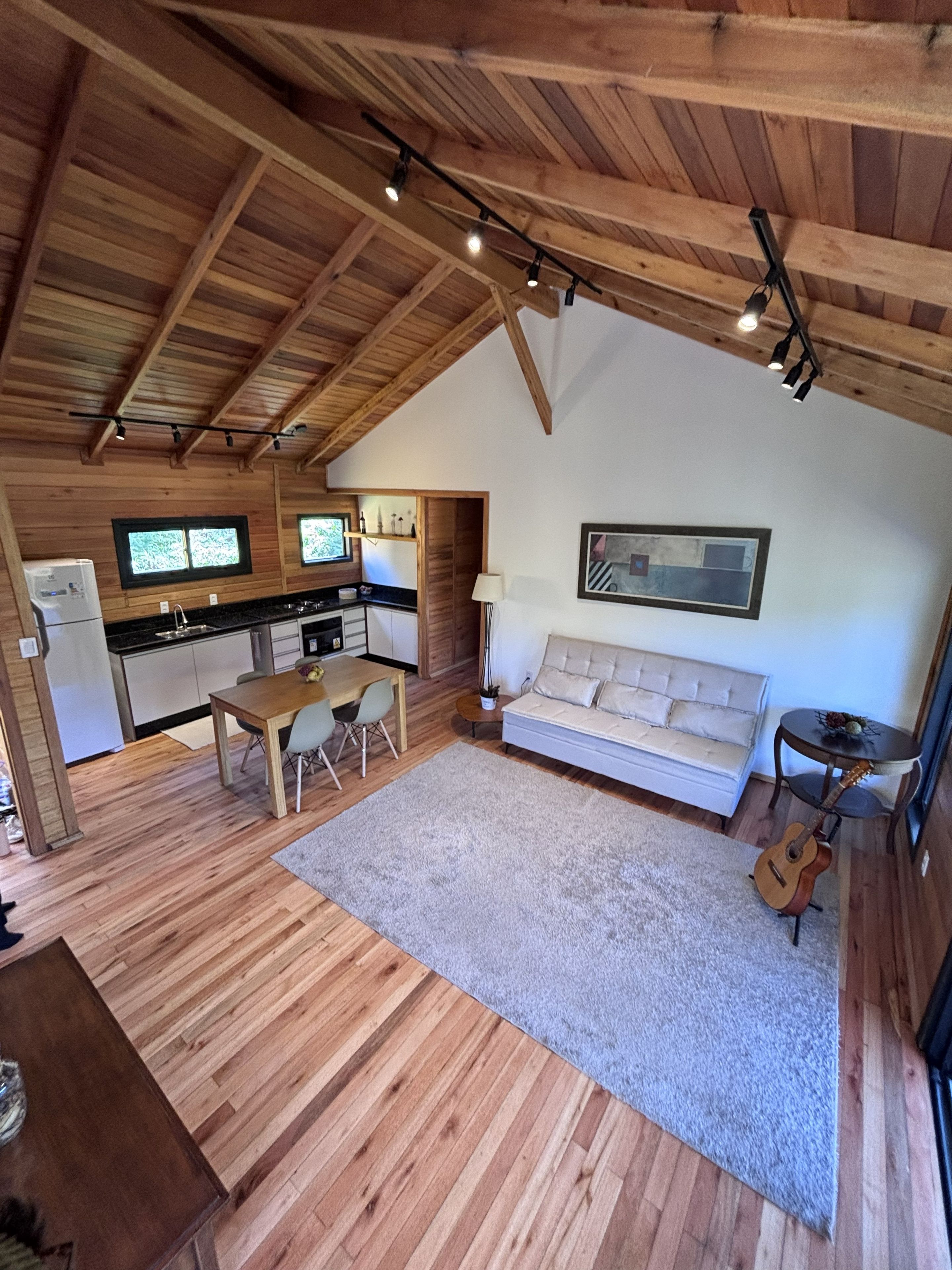 Un interior acogedor con techo de madera, un sofá, una mesa de comedor y una zona de cocina.